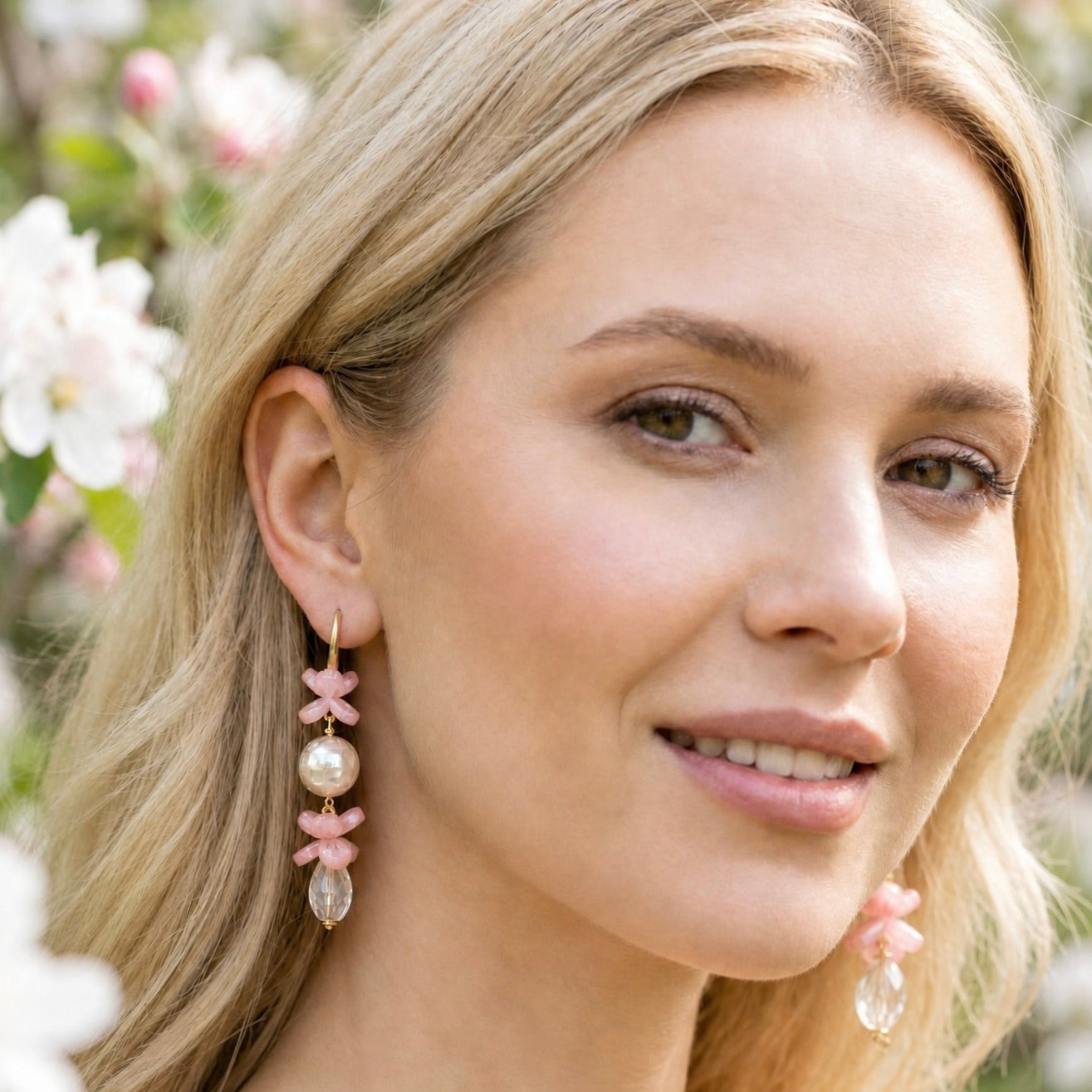 Close-up of a woman wearing the Bellini Blossom earrings against a blurred natural background.